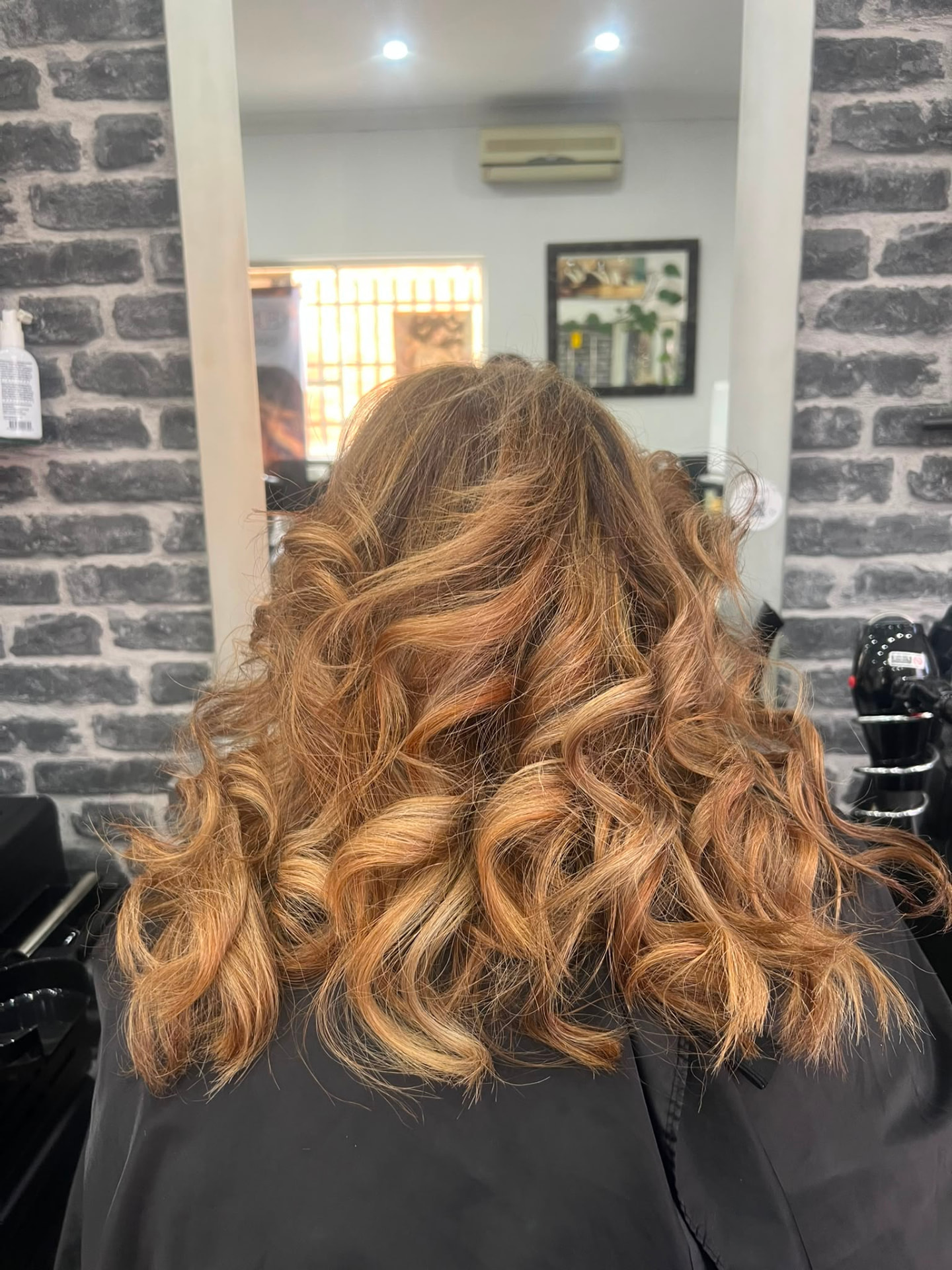 Voluminous copper curls viewed from the back after salon styling